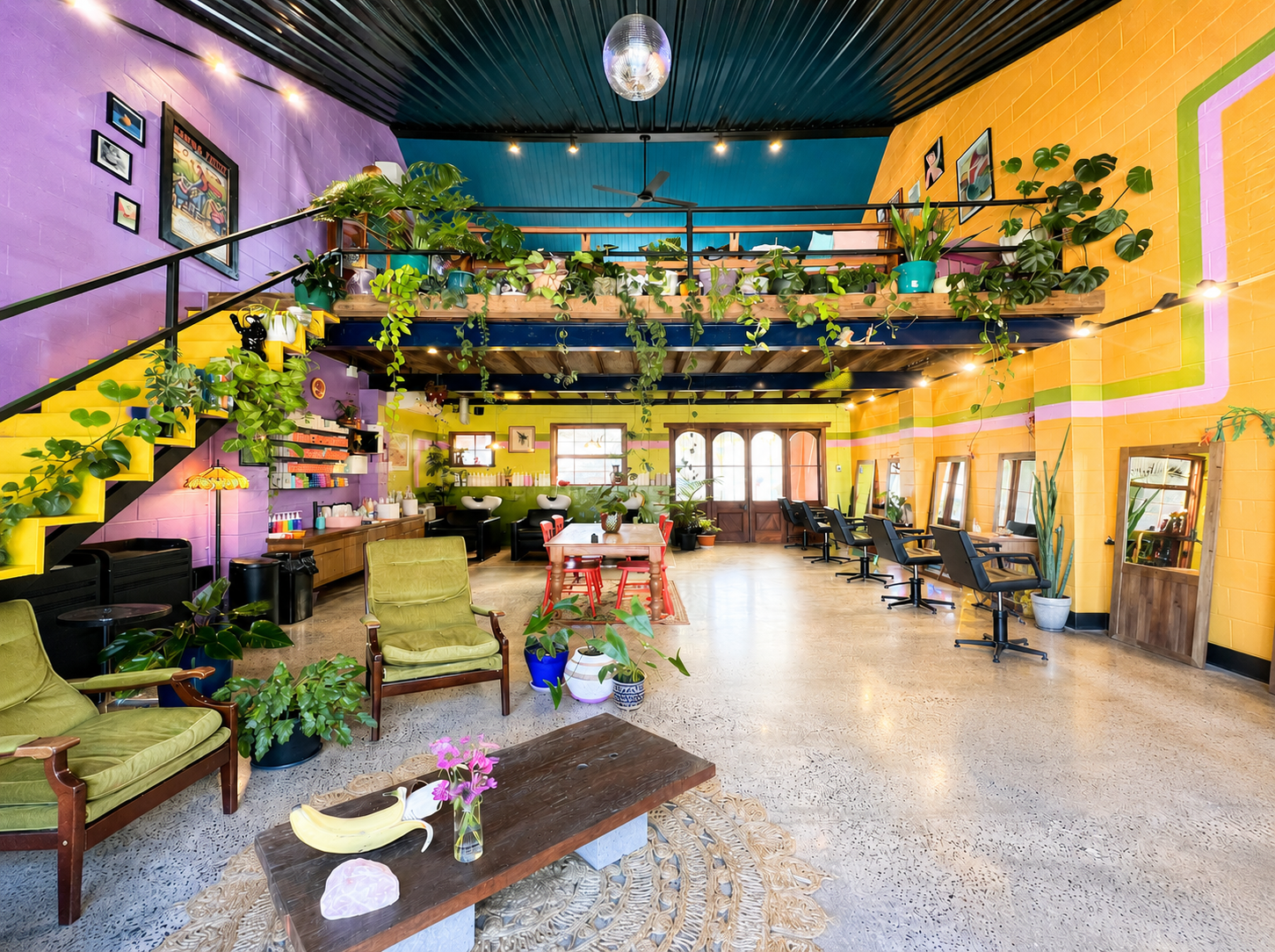 Hairjesus salon service area with orange walls, plants and stylists