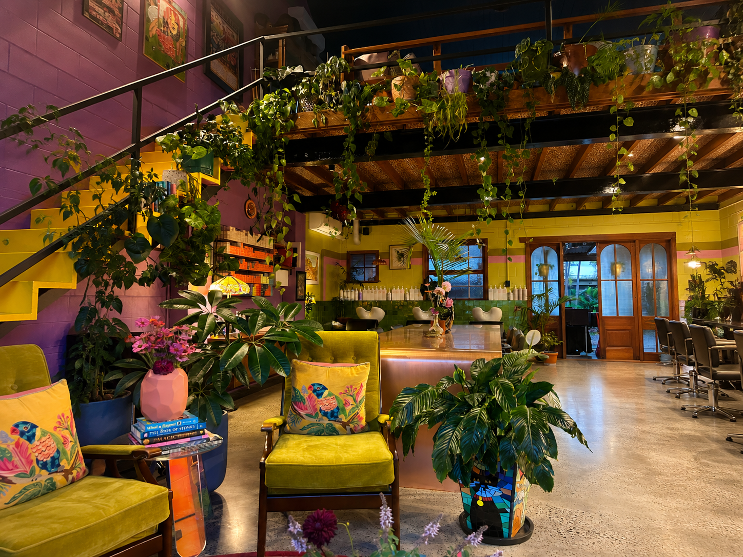 Hairjesus lounge area with yellow chairs, greenery and warm lighting